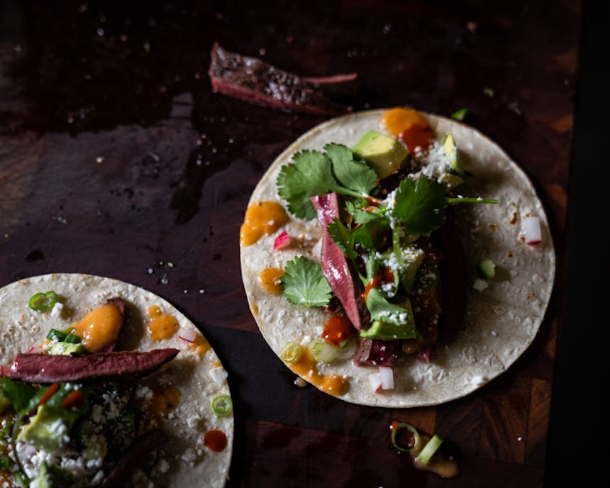 elk heart tacos with orange salsa and gresh herbs and white cotija cheese on corn tortillas