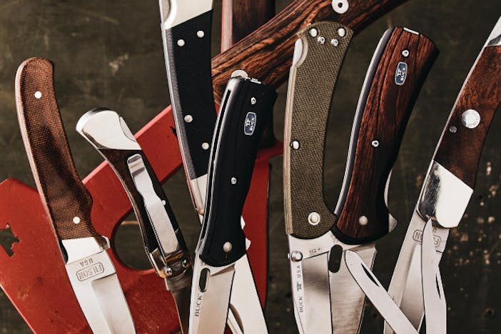 collection of filson/buck folding knives and an axe