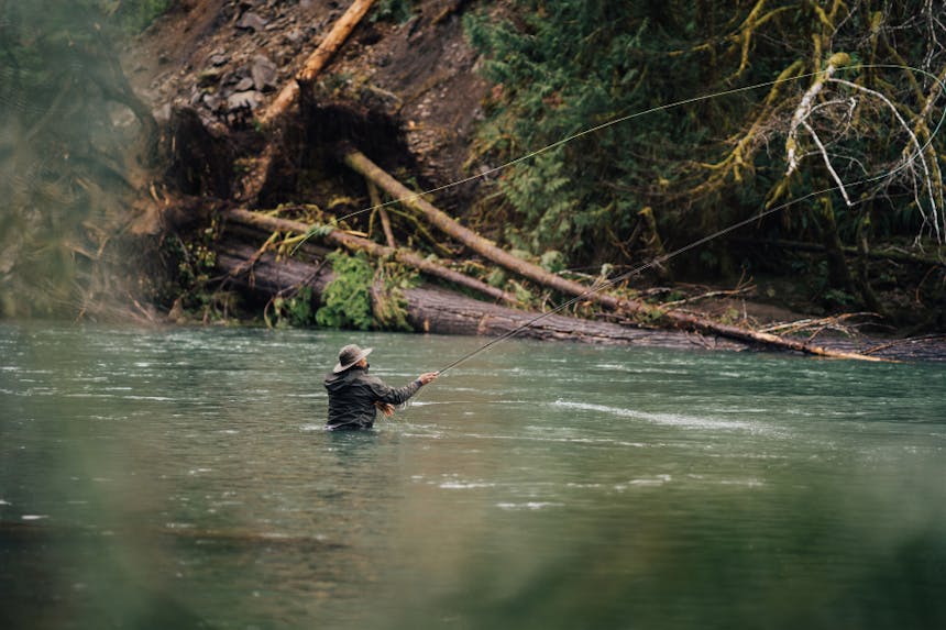 man in chest high water casting a fly fishing rod