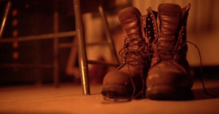 two partially laced boots sitting next to a chair
