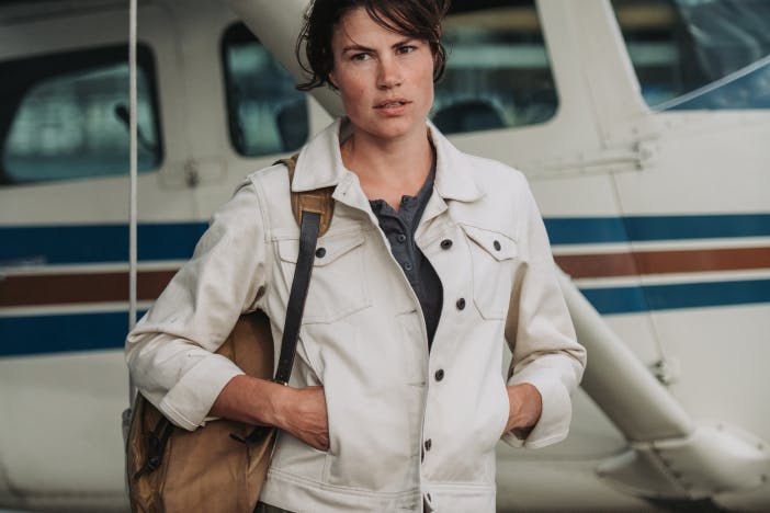 woman with white jacket standing in front of a small plane