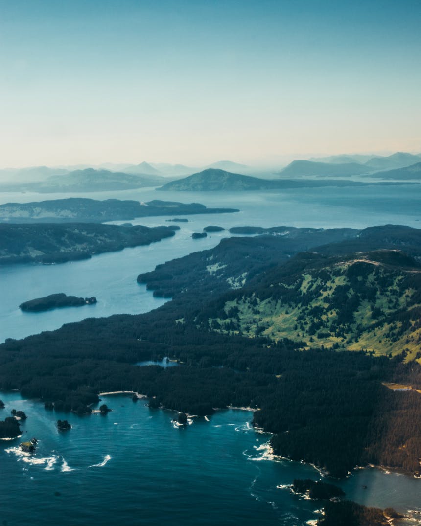 aerial image of low lying trees in marshland with hills rising above and rolling hills extending to the horizon