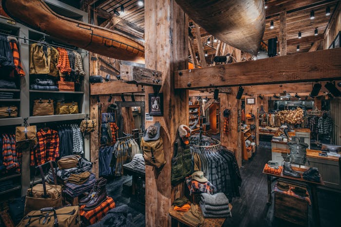 interior image of filson flagship store in New York City. Wood beams have clothes and bags hanging on them, bags and shirts hang on shelves on the walls
