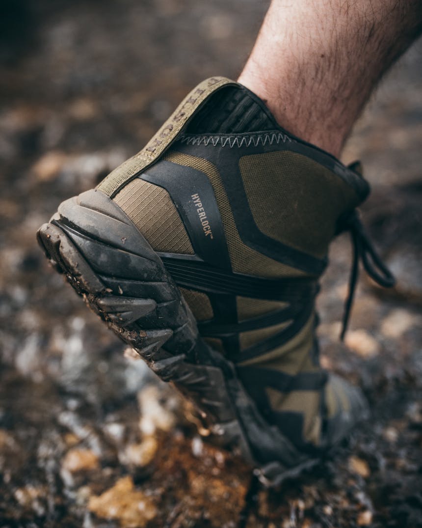 foot in filson/merrell hiking shoe extended in demi-pointe on muddy trail