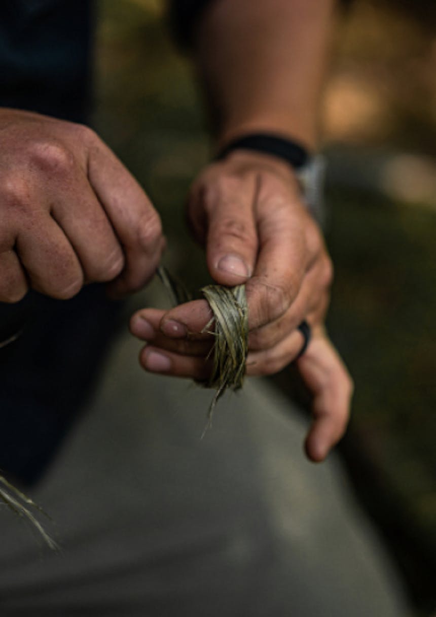 hand wrapping stinging nettle cordage around three fingers