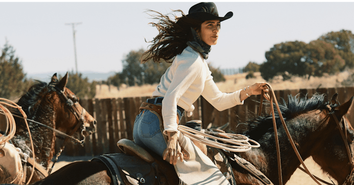 woman in white shirt and jeans riding a horse