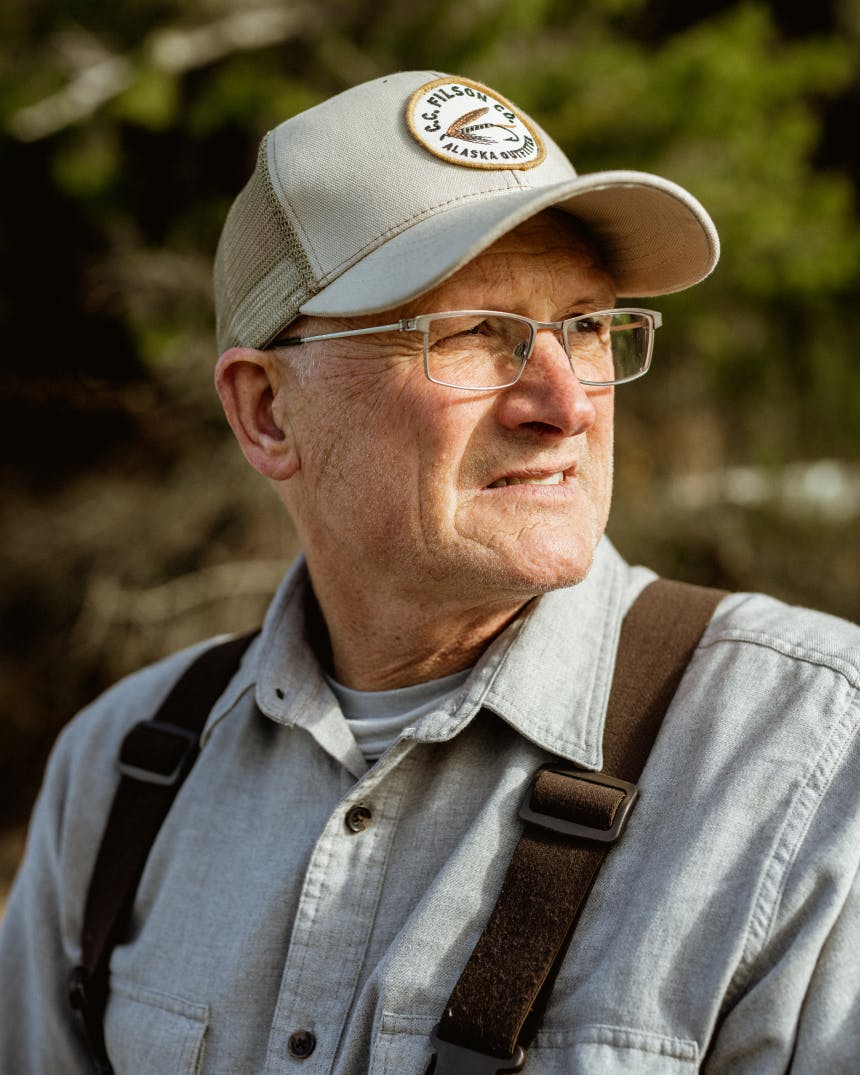 old man wearing a tan hat and a light blue shirt with brown suspenders