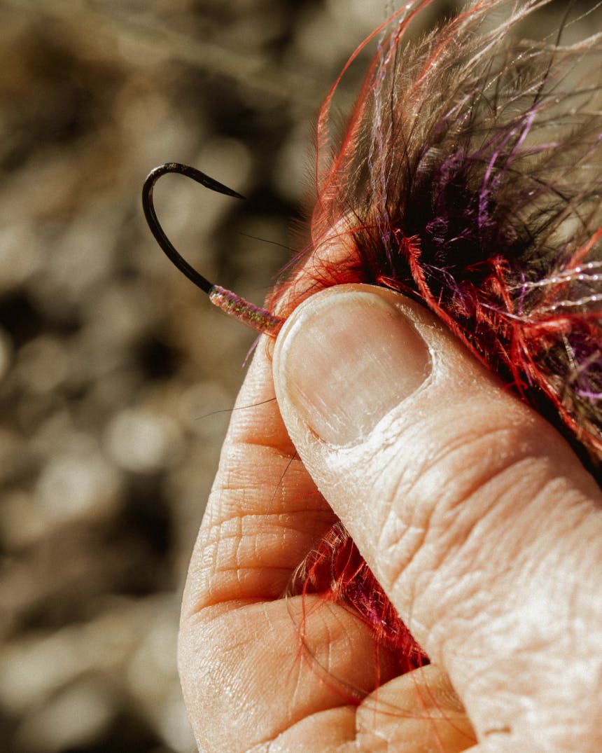closeup detail of hand holding a hook between a thumb and first finger