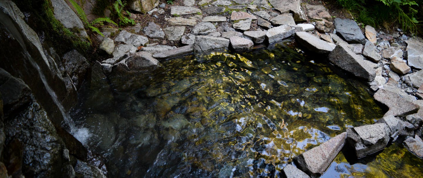 a shimmering pool of water lined by angular rock slabs