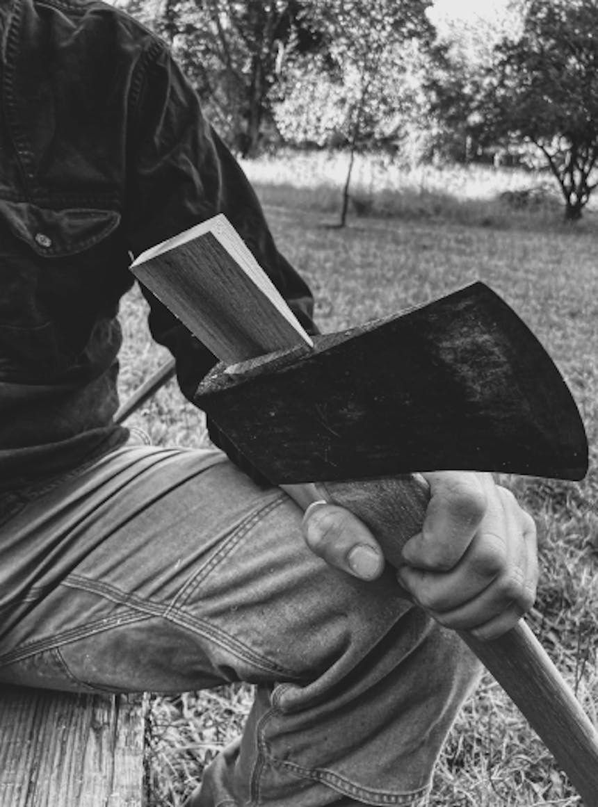 person working on fitting an axe head onto a handle