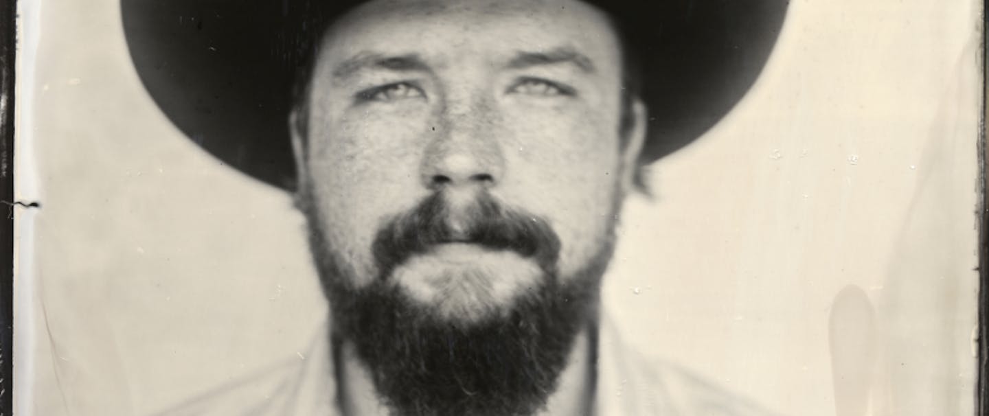 black and white portrait of man in black cowboy hat with beard
