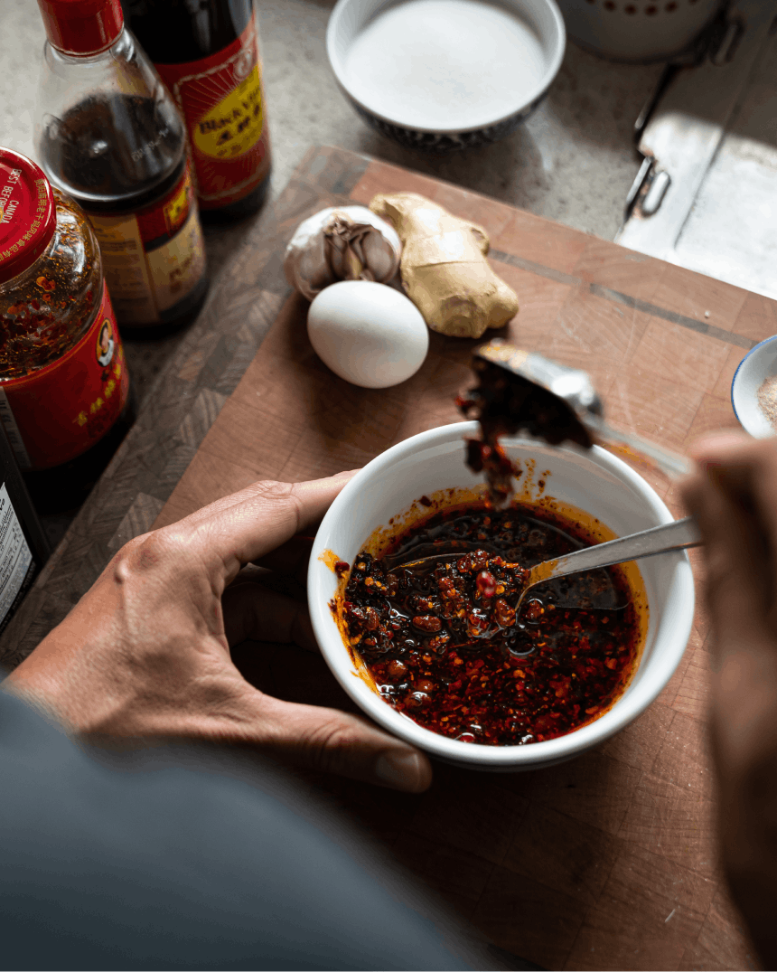 hand spooning chili into chili oil