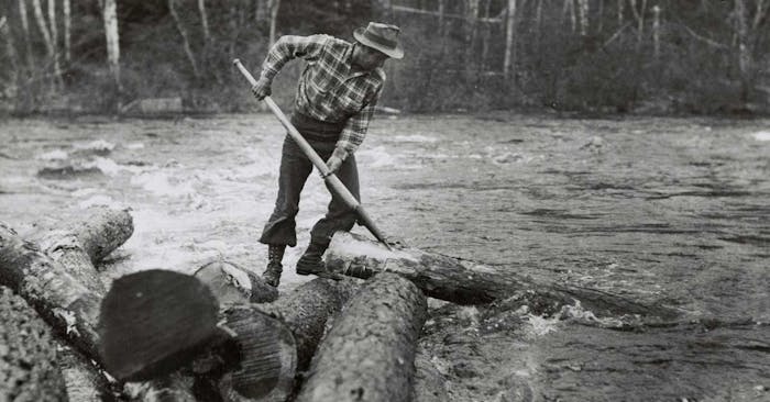 logger using a tool to manipulate a log in a river