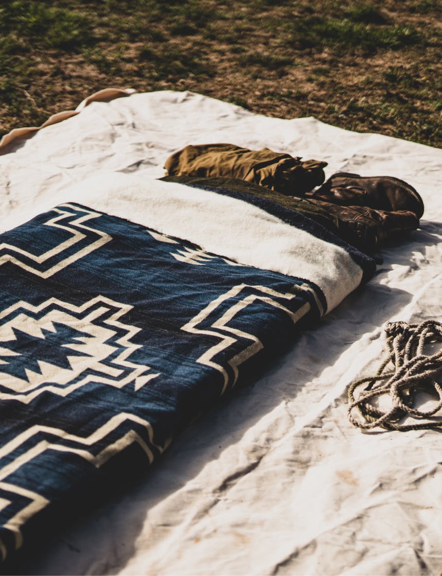 a canvas bedroll with a woven native american style blanket in a grassy field