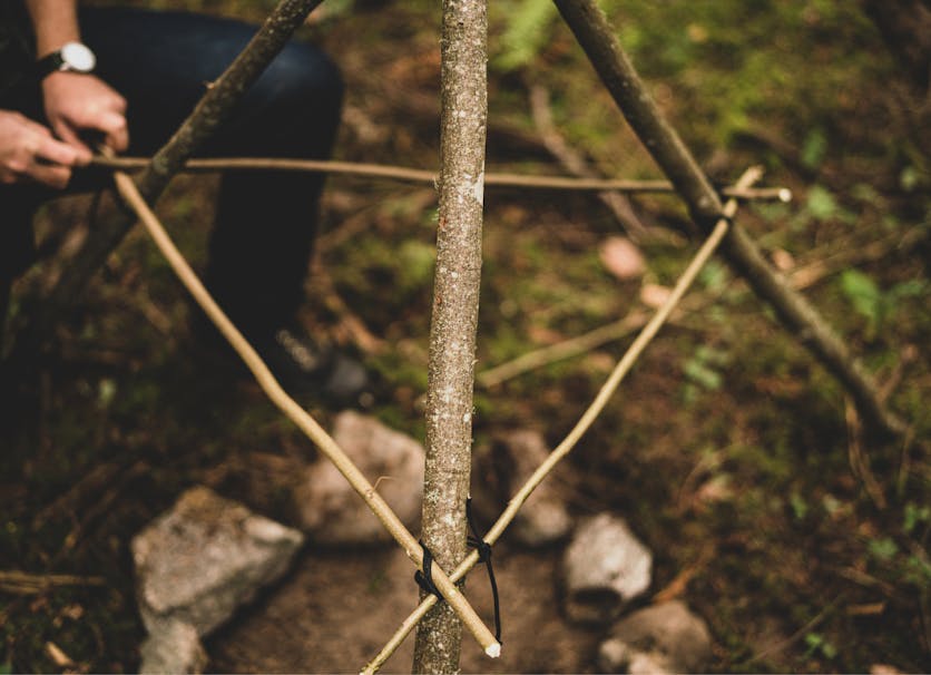 person setting up a triangular smoking rack on a wooden cooking rack