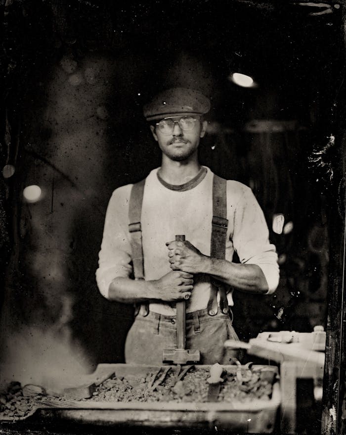 person standing at a forge holding a sledge hammer
