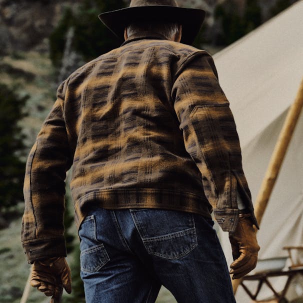 手袋を着用し、デニムの背面図を洗った茶色と黄色のフランネルの男