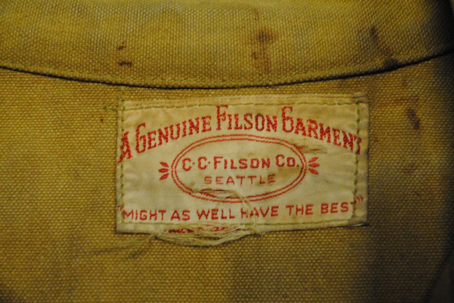 worn filson patch on tan cloth with patch text reads: A genuine Filson Garment CC Filson CO. Seattle 