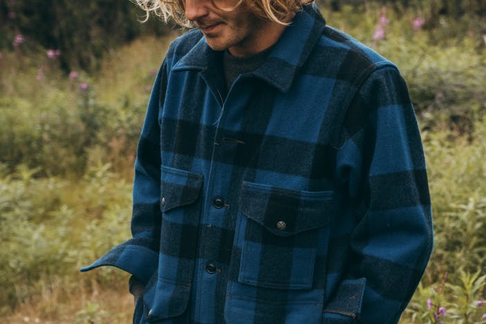 Man in meadow in heavy filson blue and navy blue plaid shirt