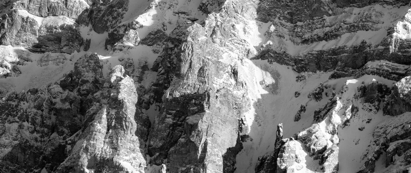 black and white image of an imposing snow covered rocky mountain peak