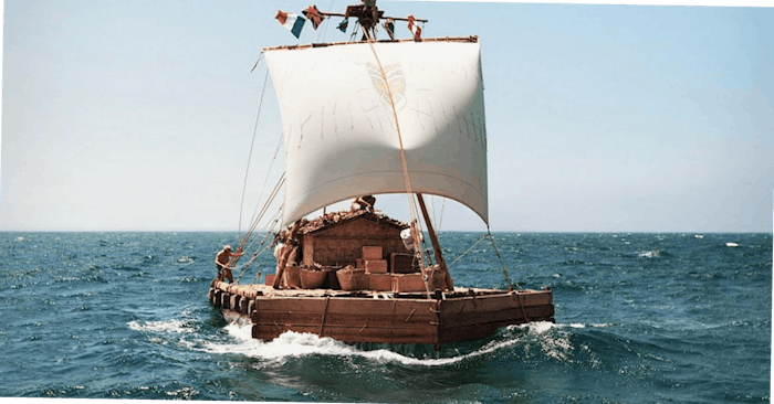 wooden raft at sea with single sail being steered by a man