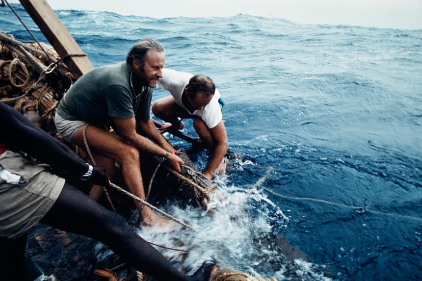 three men pulling in a line while on a raft