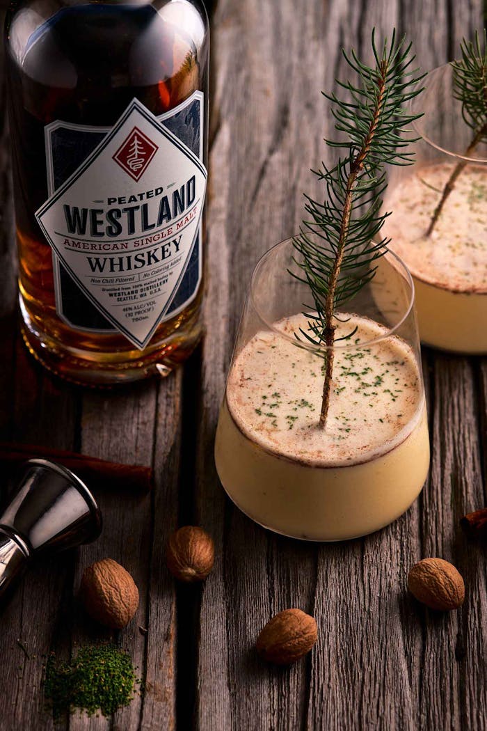 westland whiskey cocktail in two glasses next to a bottle of westland whiskey on a wooden table