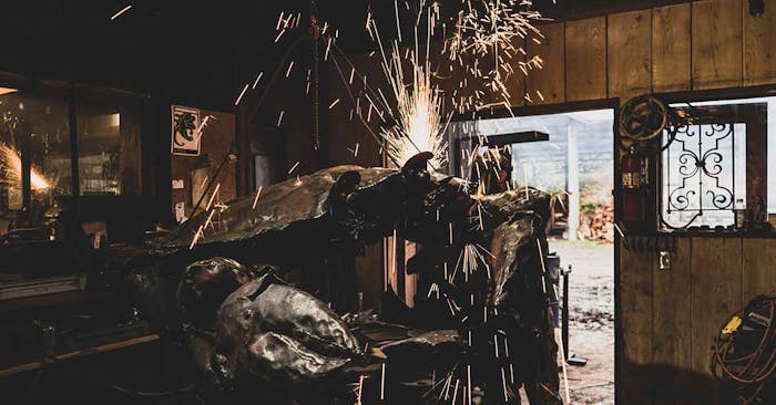 person in a workshop using an angle grinder producing large amounts of sparks on a piece of metal