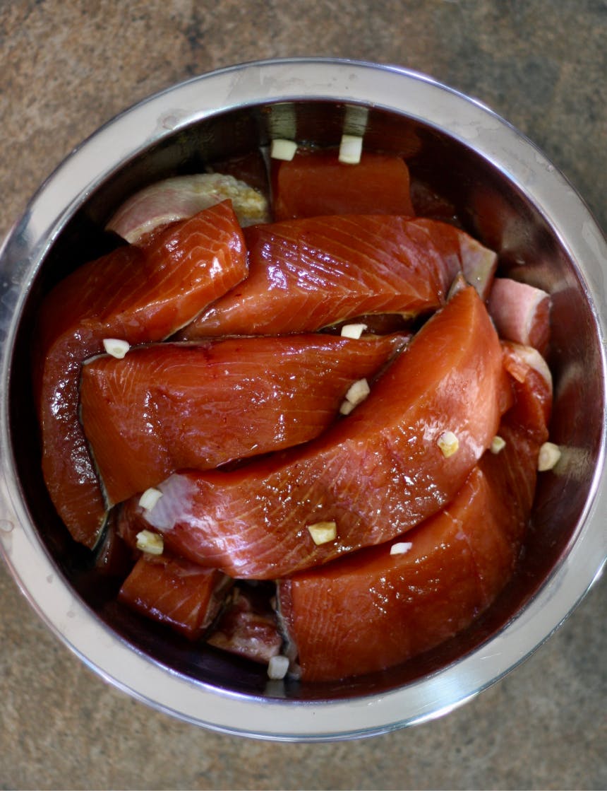 marinating pieces of salmon in a stainless steel bowl