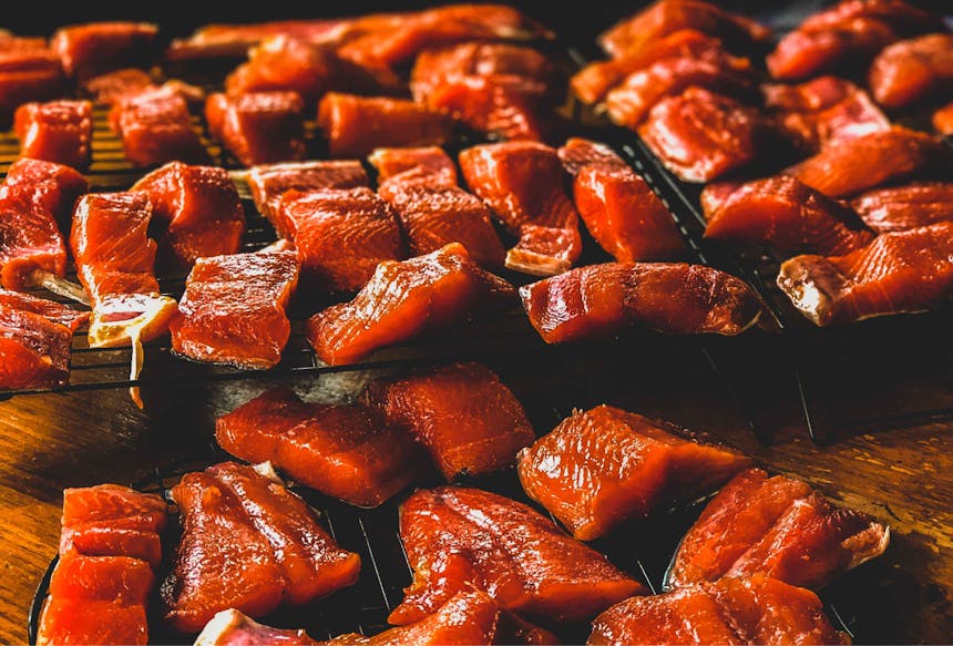 smoked salmon chunks on a grate on a wooden bar top