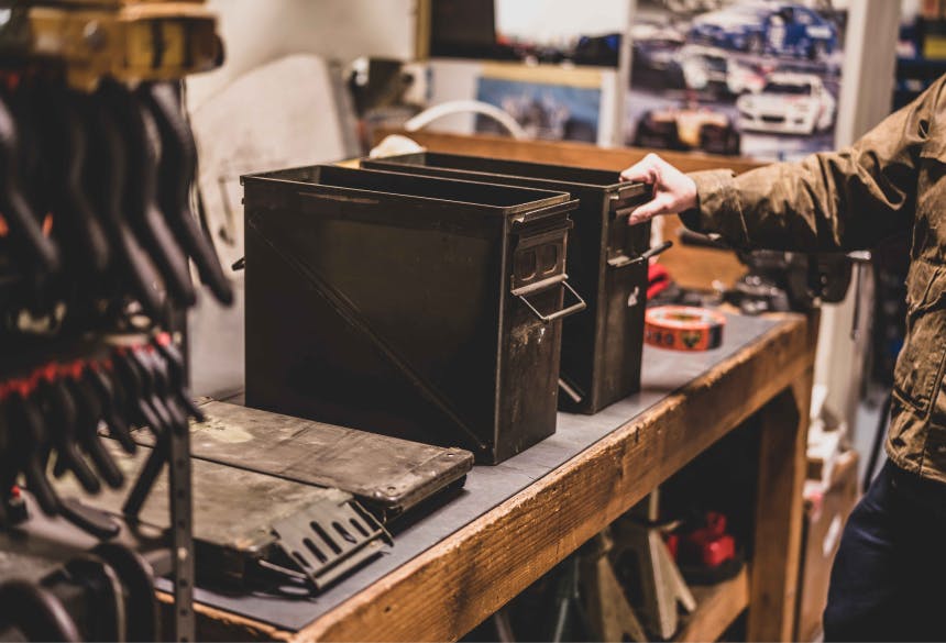 hand holding an open ammo cannister on a workbench in a garage