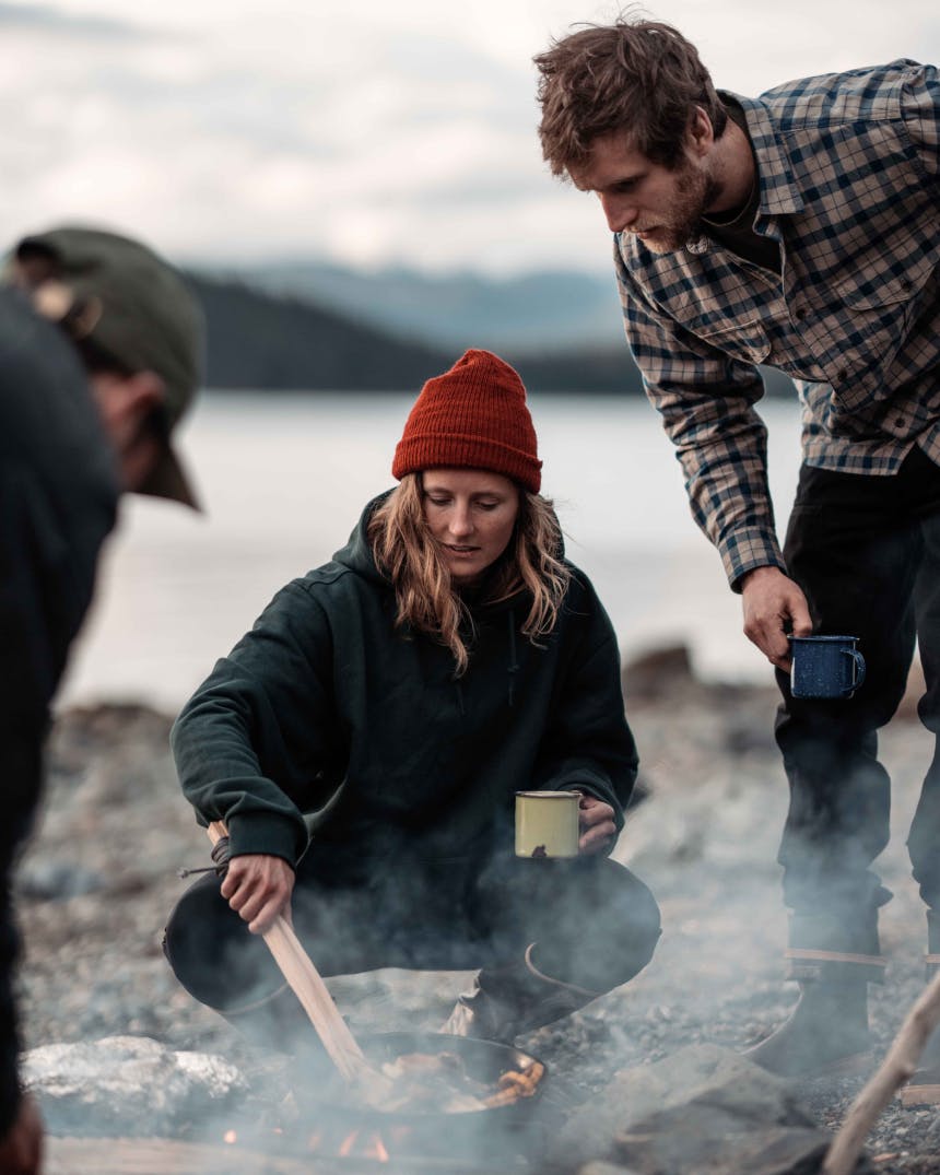 Woman cooking over an open fire on the beach in Alaska.