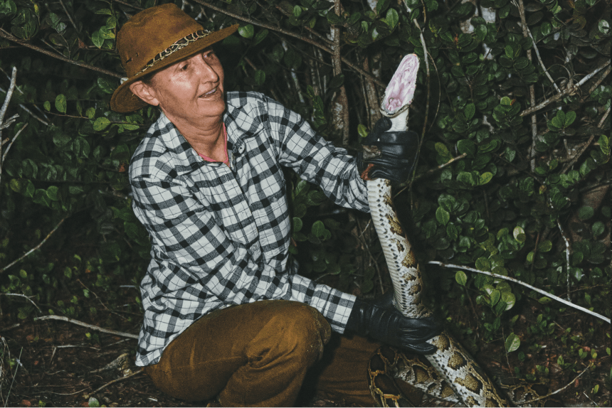 Woman holding large Burmese python.