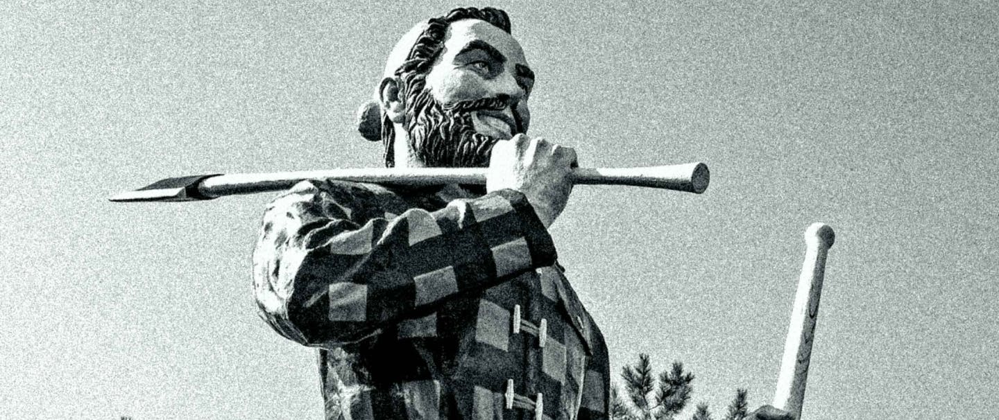 a tall Paul Bunyan statue wearing a flannel and hat, holding an axe over his shoulder and another in the opposing hand towards the ground