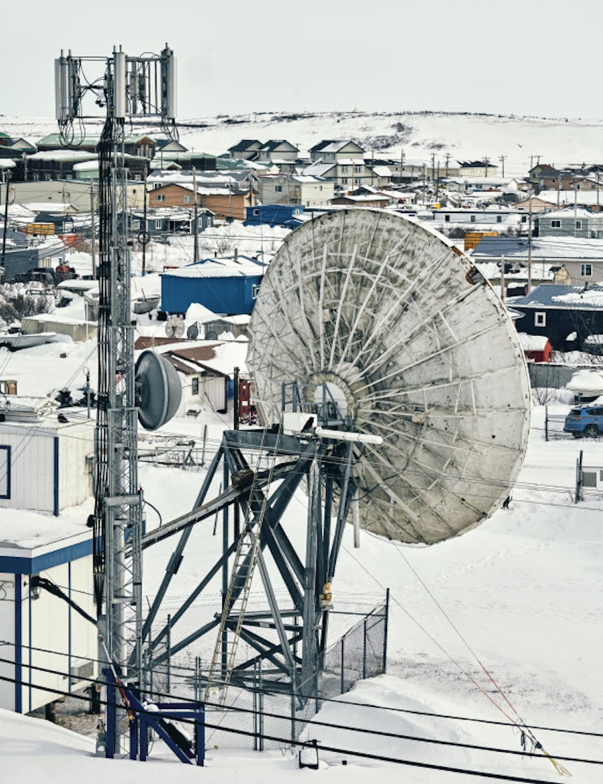 a small town in Alaska where you can see snow covered homes and satellite towers in the foreground