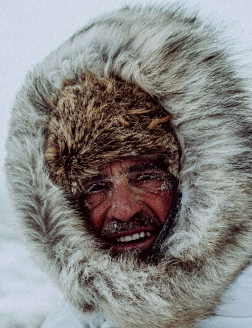 portrait of a man wearing animal fur in the blustery arctic with frozen eyelashes and facial hair