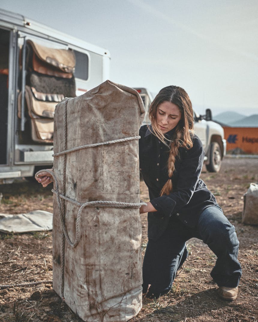 Woman tying knots on a horse packing buddle