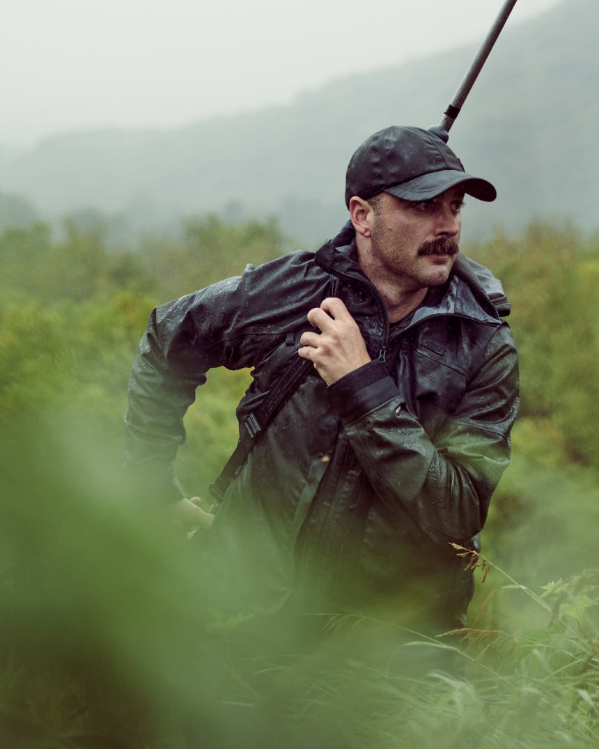 Man carrying rifle through Alaskan wilderness