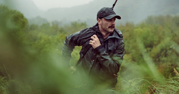 Man carrying rifle through Alaskan wilderness