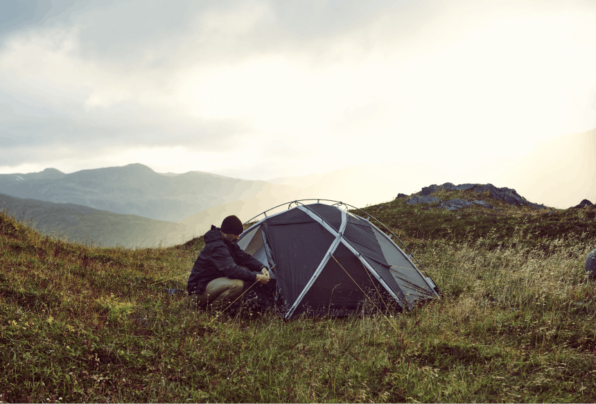 Man setting up tent on mountain top