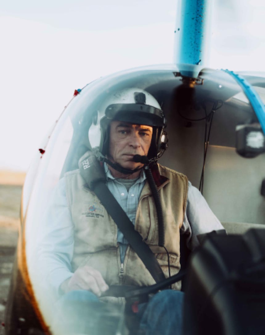 close up of a older white man inside a two person helicopter ready to take off
