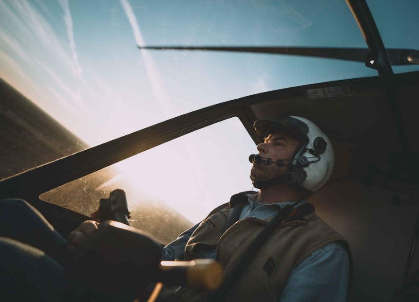 a close up of a pilot flying a helicopter and seeing the propeller swinging overhead through the glass