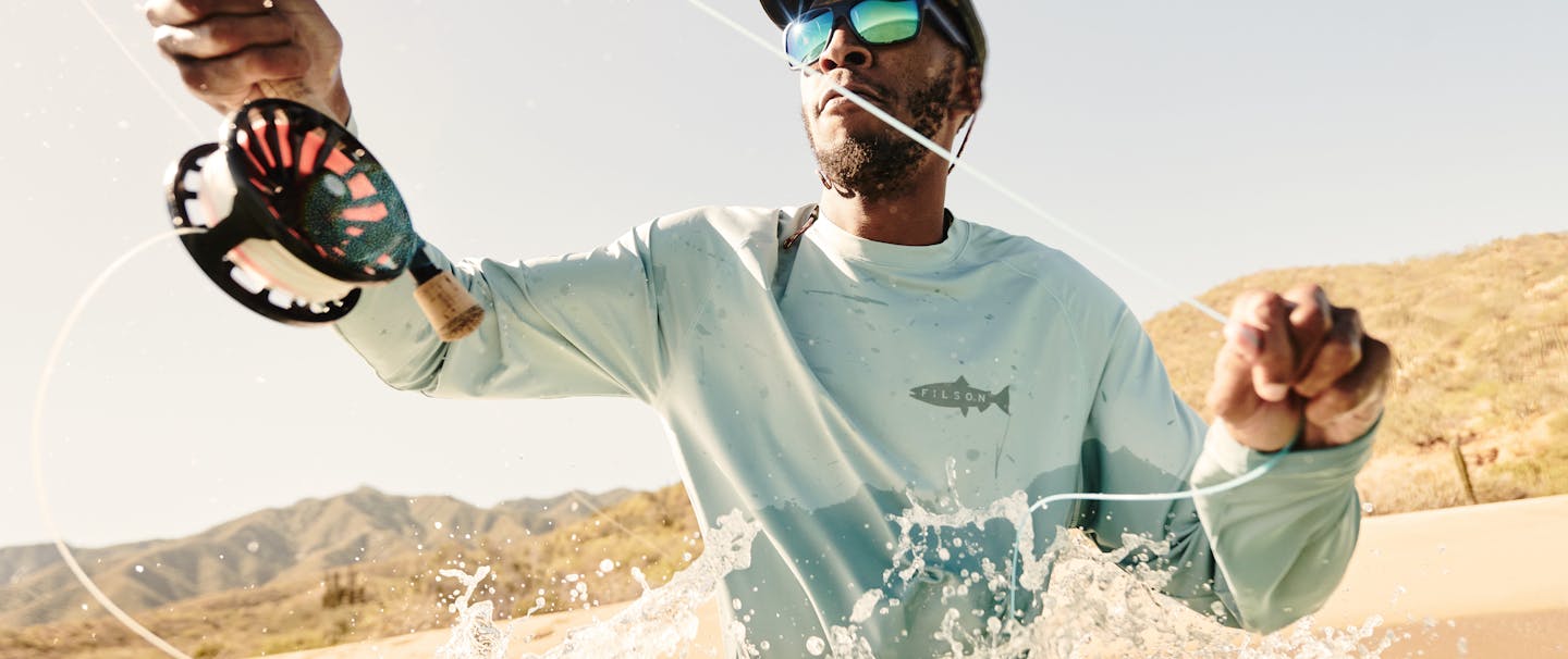 close up of an African American man wearing a long sleeve blue shirt fly fishing
