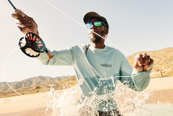 close up of an African American man wearing a long sleeve blue shirt fly fishing