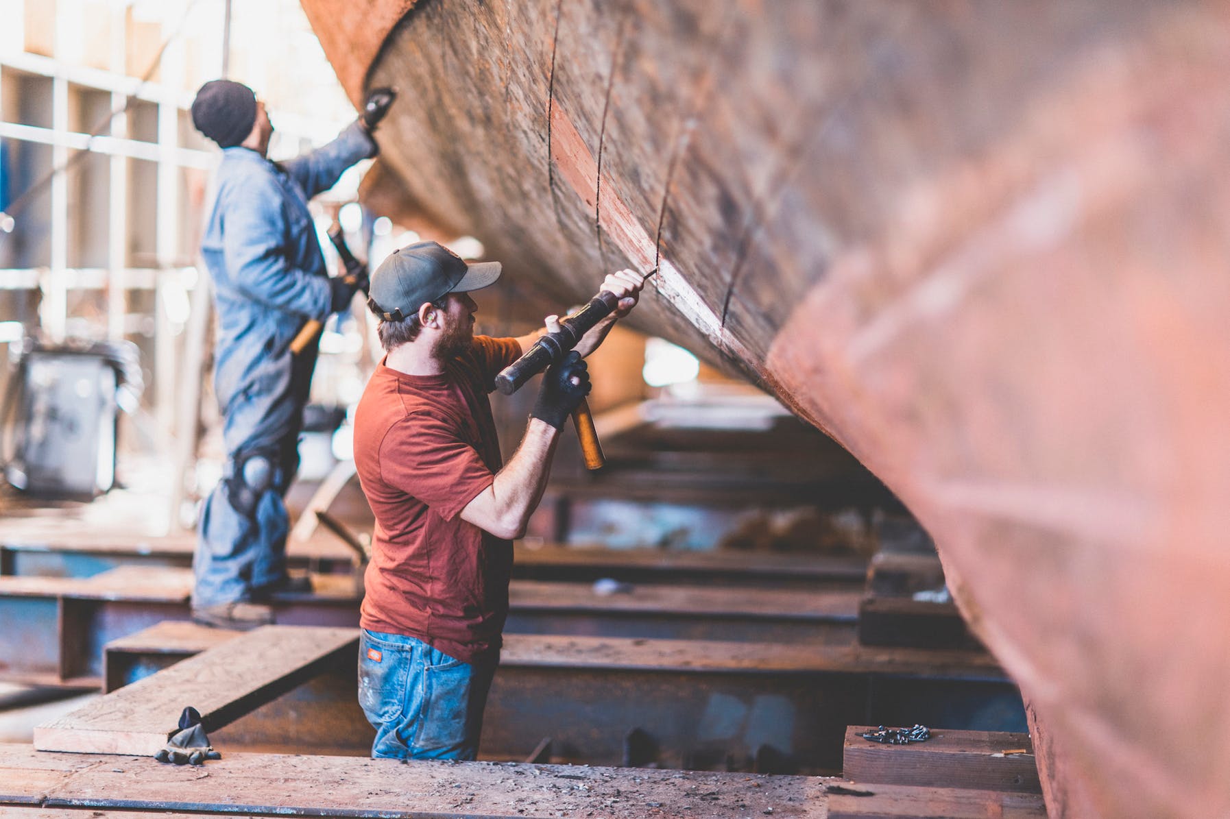 Men working on the exterior hull of a boat in a dry dock.