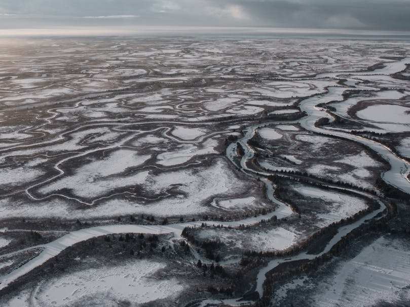 frozen river lists through open expanse of barren snowy land