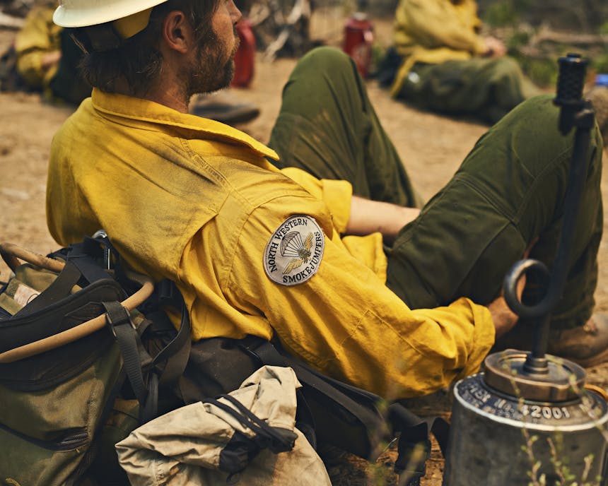Smokejumper resting outside in yellow jacket and green pants