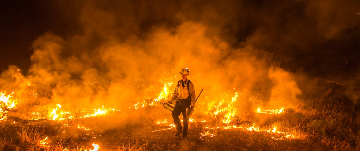 fire fighter in grass surrounded by fire