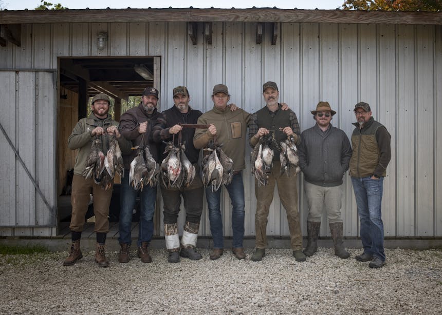 group of men with the take from the hunt outside white trailer