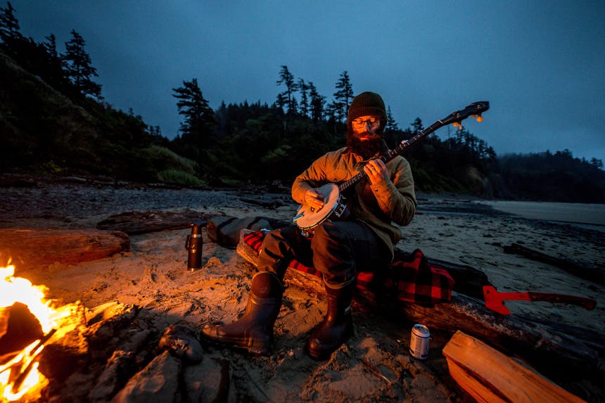 eric playing his banjo by a camp fire